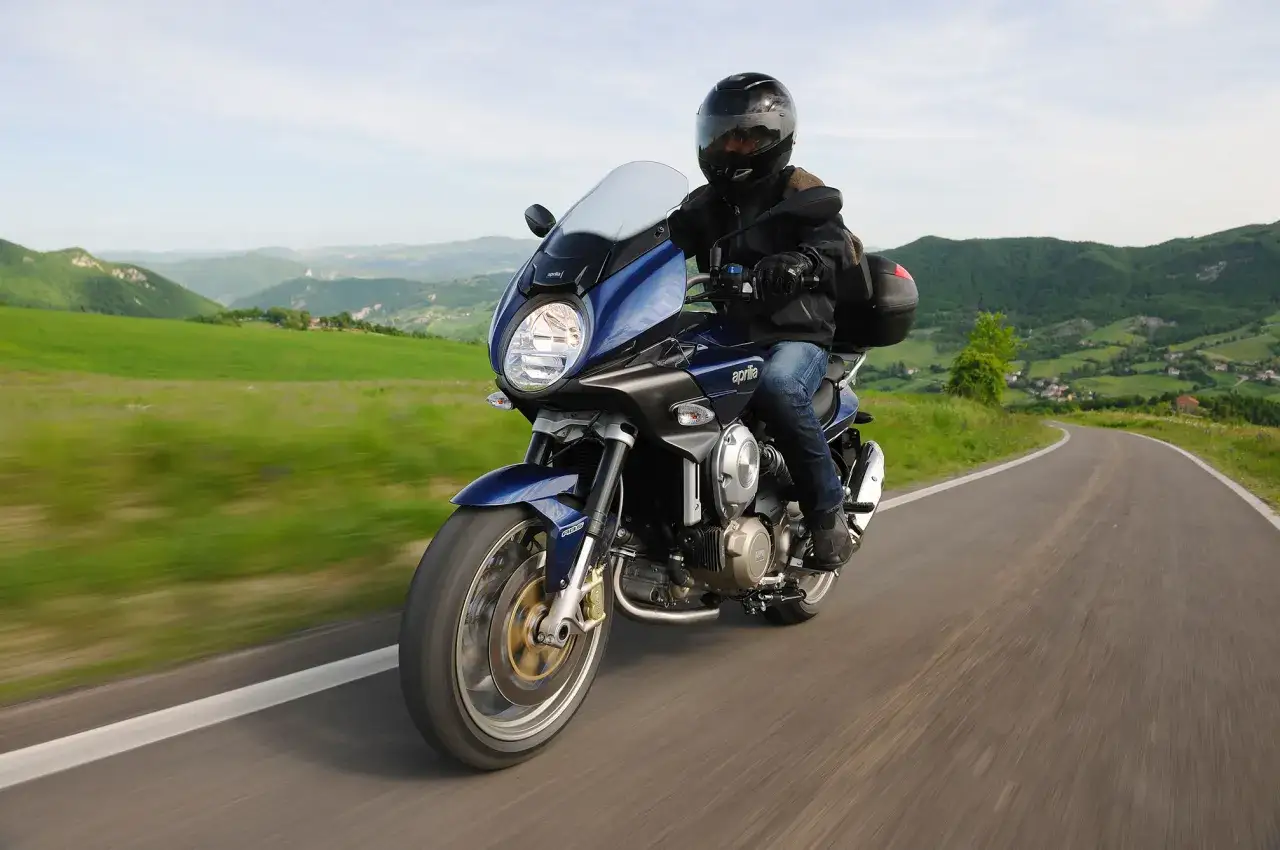 Motocykle szosowo turystyczne przemierzają malownicze, zielone wzgórza.