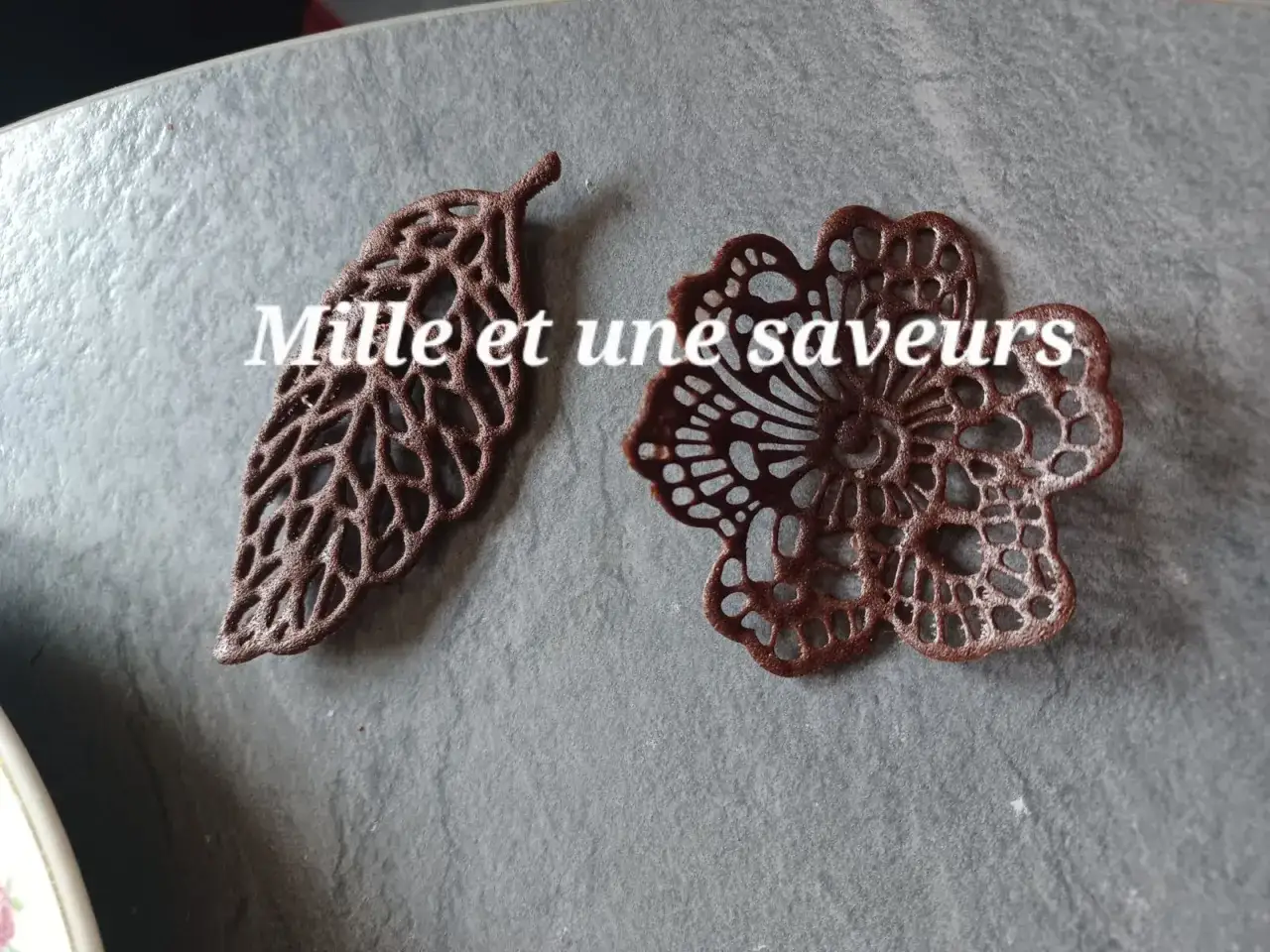 Délicates décorations en chocolat, une feuille et une fleur, réalisées avec une pâte à cigarette fine.