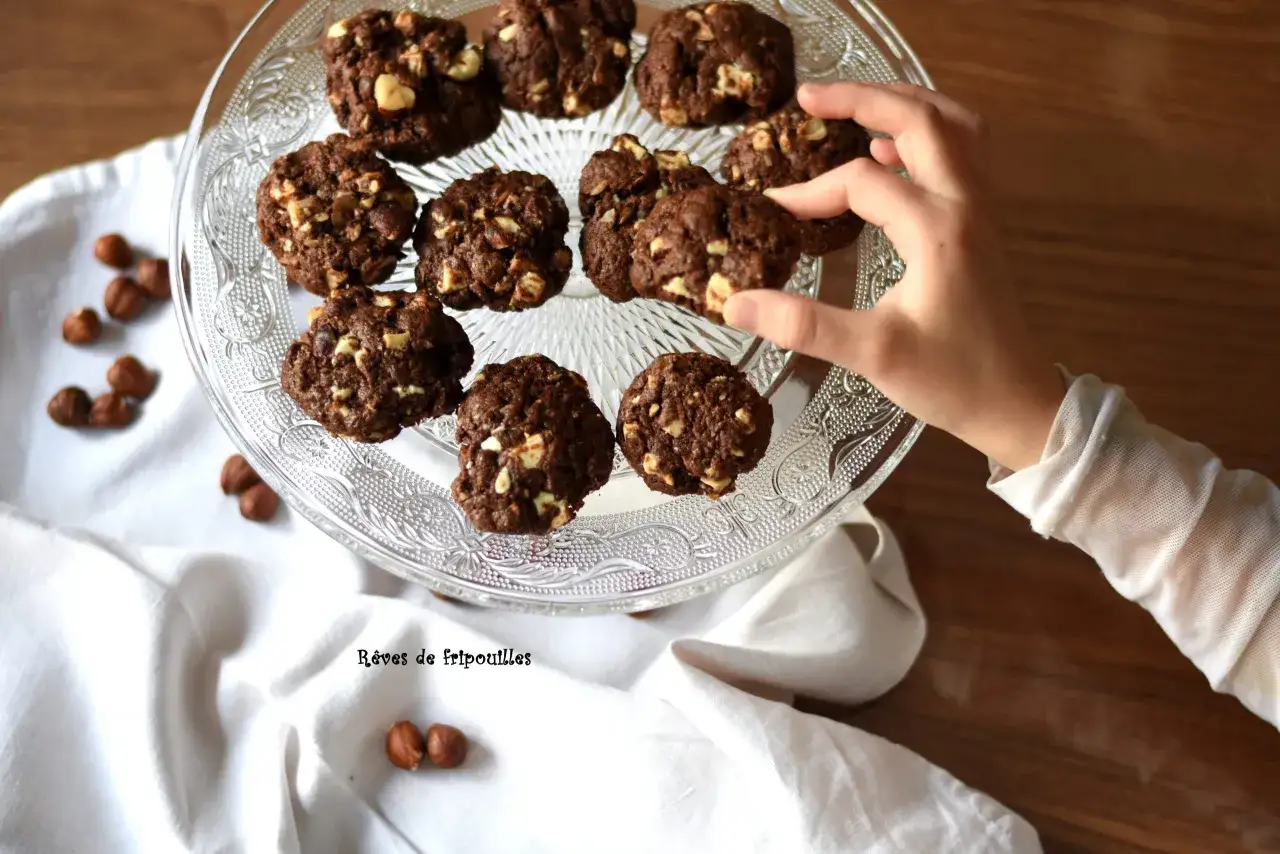 Délicieux cookies au chocolat et noisettes, parfaits pour savoir que faire avec un reste de ganache au chocolat. Une main en prend un.