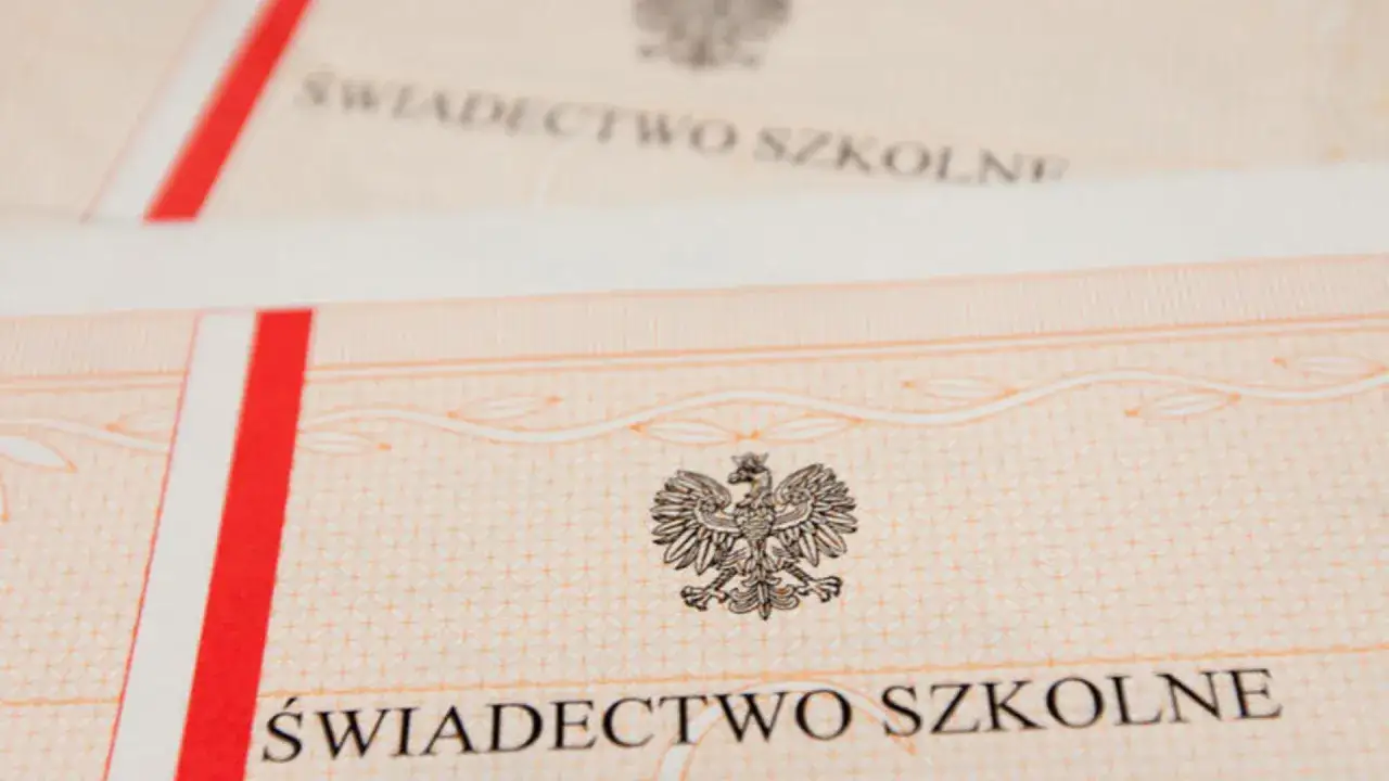 Zbliżenie na świadectwo szkolne z godłem Polski. Czerwono-biały pasek po lewej stronie.