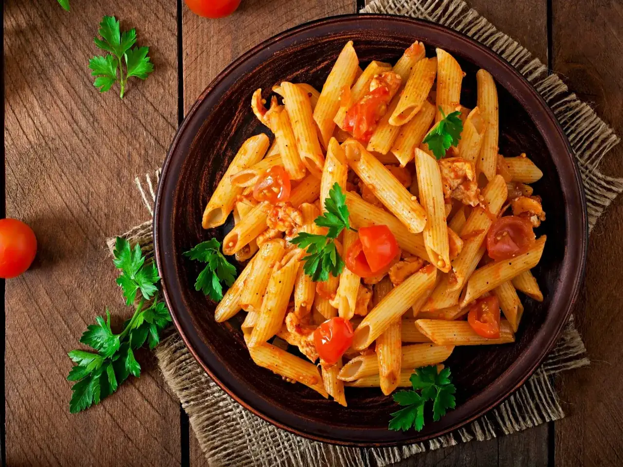 Penne z kurczakiem i pomidorami, udekorowane natką pietruszki. Idealne pytanie: co dzisiaj ugotować na obiad?