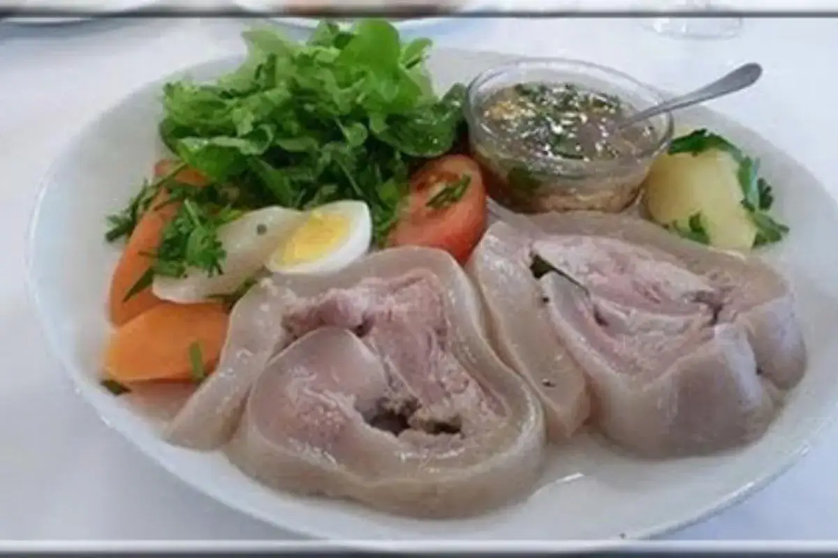 Tête de veau en cocotte, servie avec des légumes, un œuf dur et une sauce vinaigrette. Un plat traditionnel savoureux.