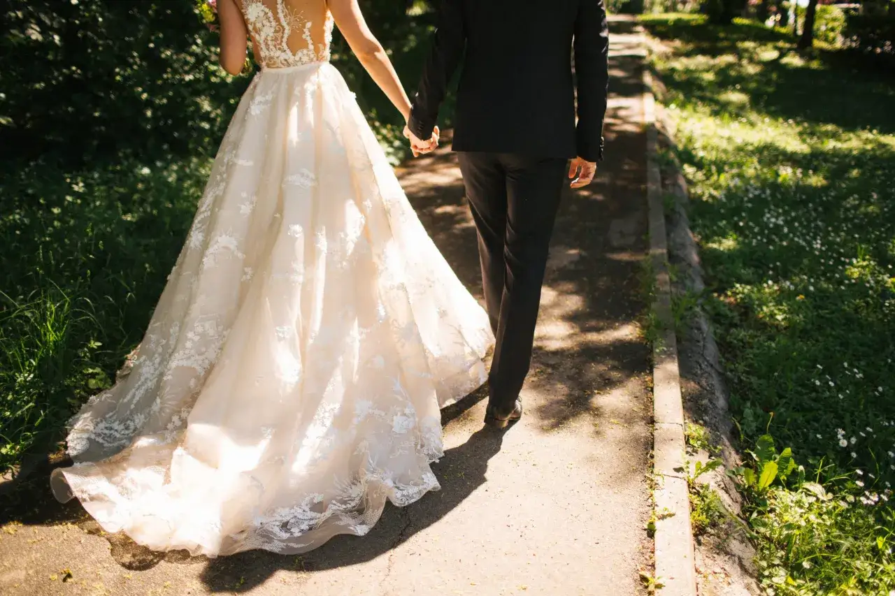 Para zjawiskowa suknia ślubna i elegancki garnitur idący ręka w rękę. Jak zareagować na zawiadomienie o ślubie?
