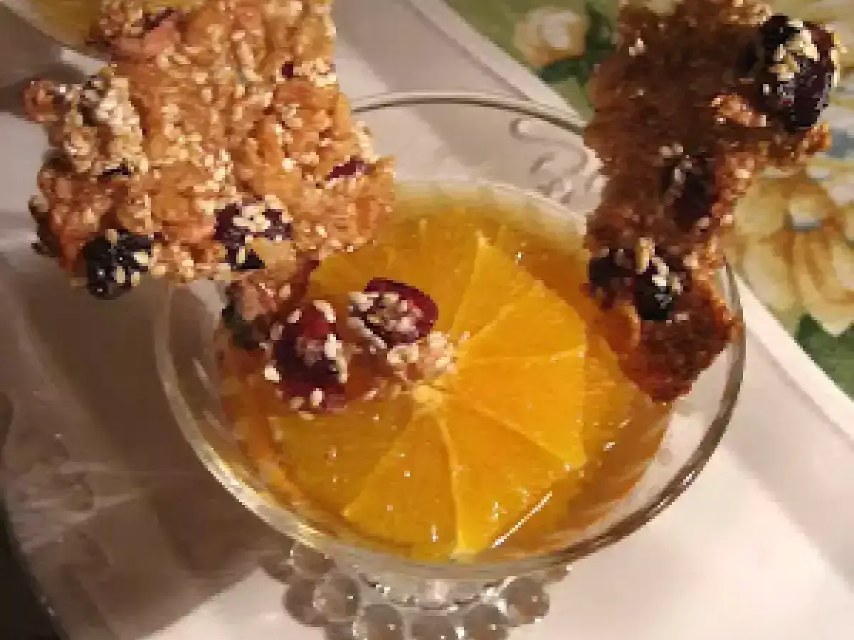 Délicieuse tuile de riz croustillante garnie de fruits secs, posée sur une tranche d'orange dans un verre.