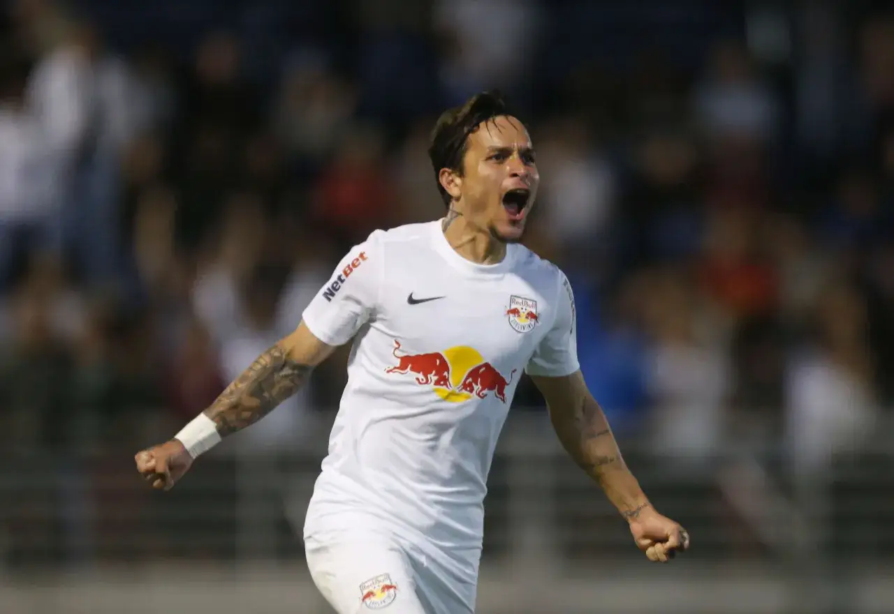 Piłkarz w białej koszulce z logo Red Bull świętuje bramkę. Wśród najlepszych brazylijskich piłkarzy, jego radość jest zaraźliwa.