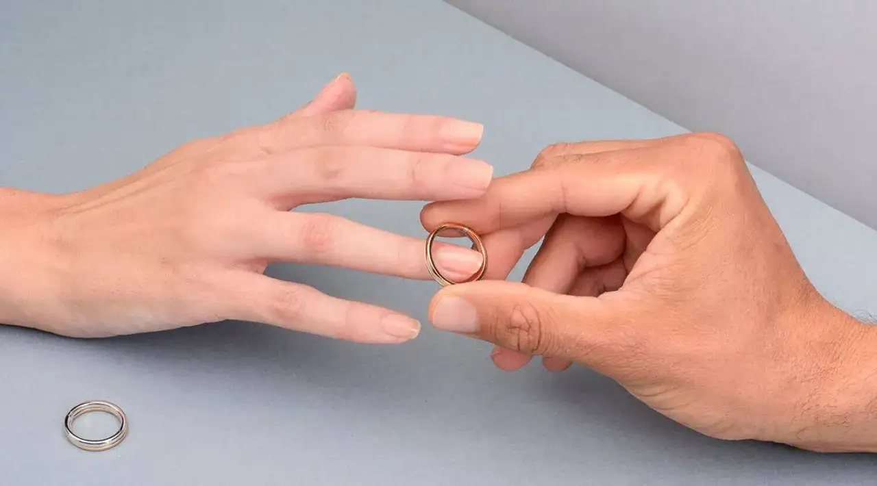 Manos unidas, un anillo dorado listo para ser colocado en el dedo anular, el lugar donde se pone el anillo de compromiso.
