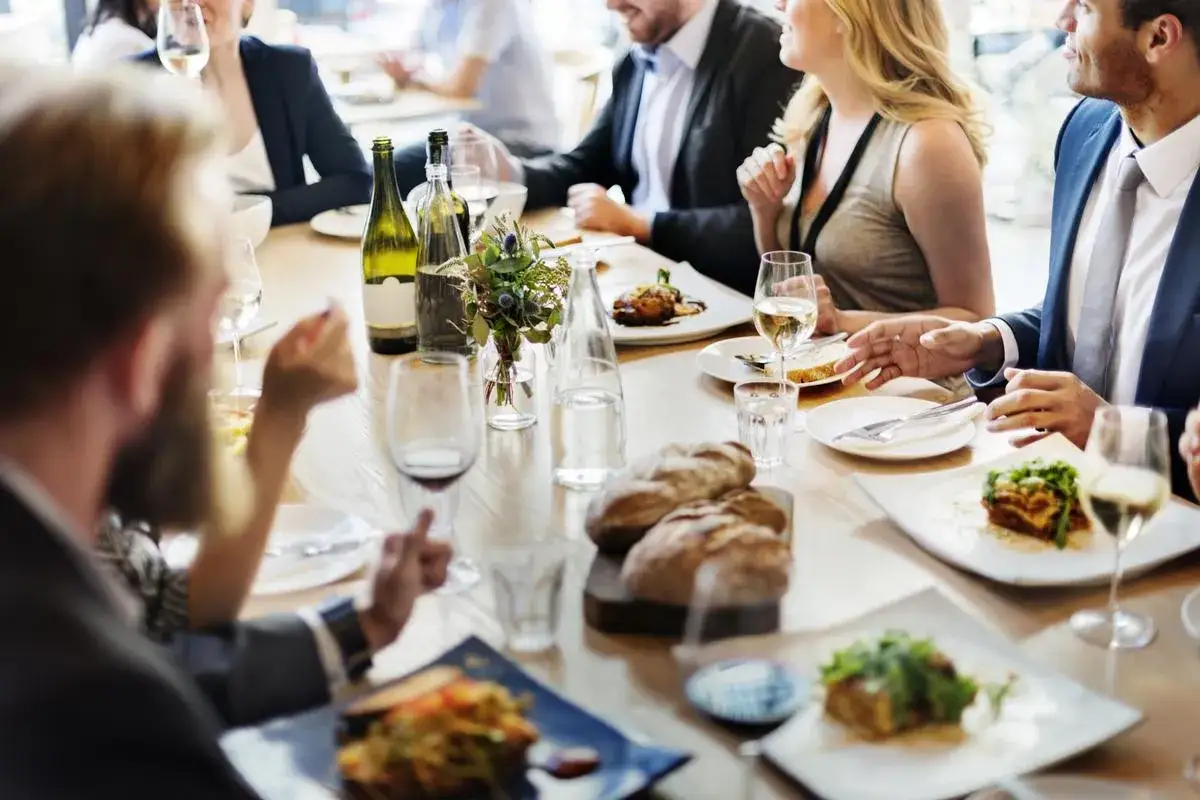 Un dîner sympa entre amis, avec des plats appétissants, du pain frais et du vin blanc sur une table en bois.
