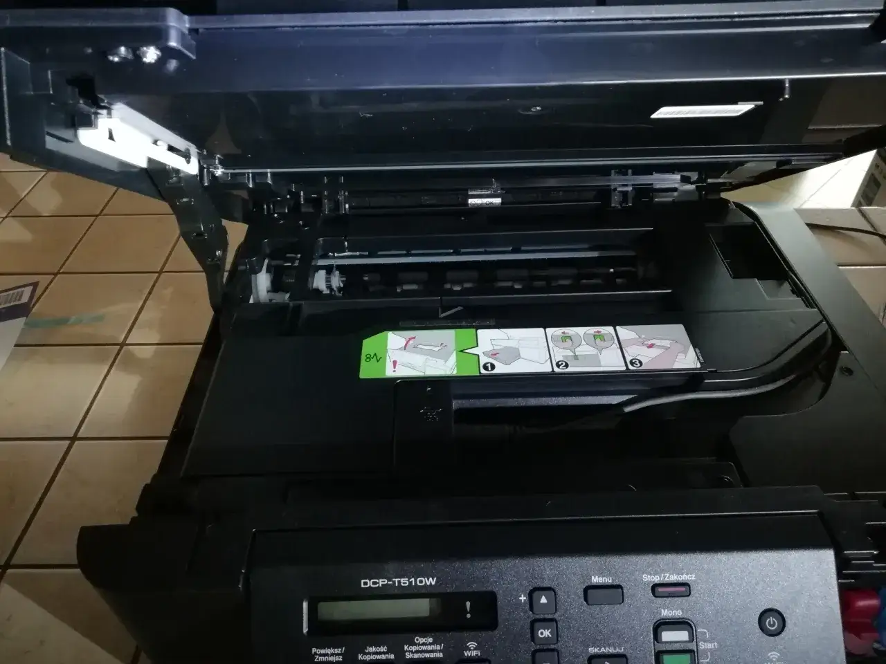 Otwarta drukarka Brother DCP-T510W z widocznymi instrukcjami i panelem sterowania.