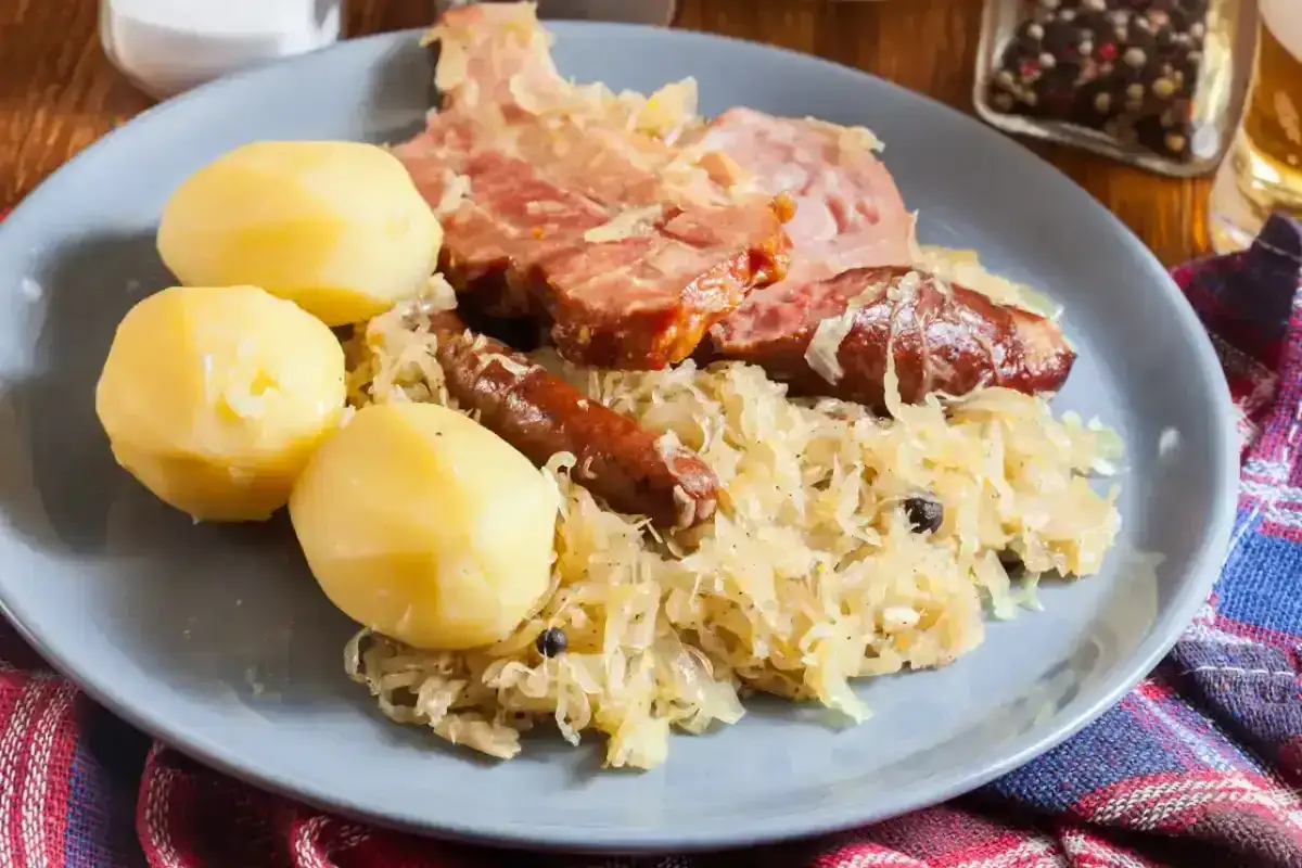 Une assiette de choucroute garnie, avec pommes de terre, saucisses et viande fumée. Un plat qui raconte une histoire culinaire.