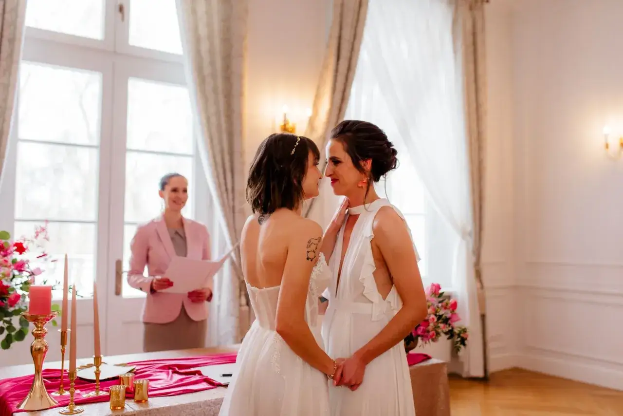 Dwie kobiety w białych sukniach ślubnych patrzą sobie w oczy podczas ceremonii. To piękny ślub homoseksualny.