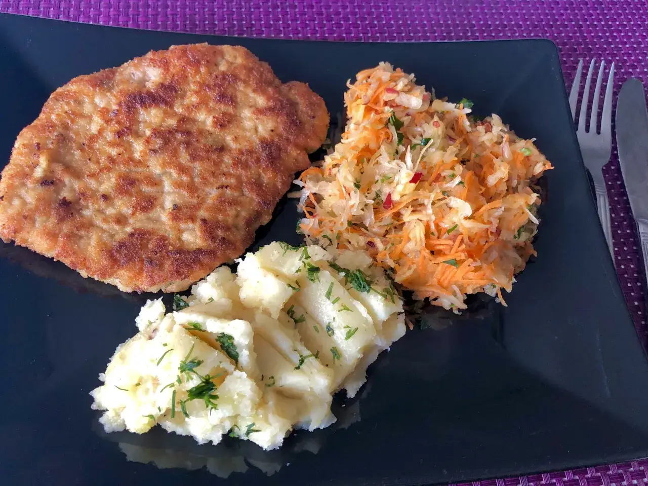 Schabowy z ziemniakami i surówką to świetny pomysł, co zrobic ze schabu na obiad. Pyszny, złocisty kotlet na talerzu.