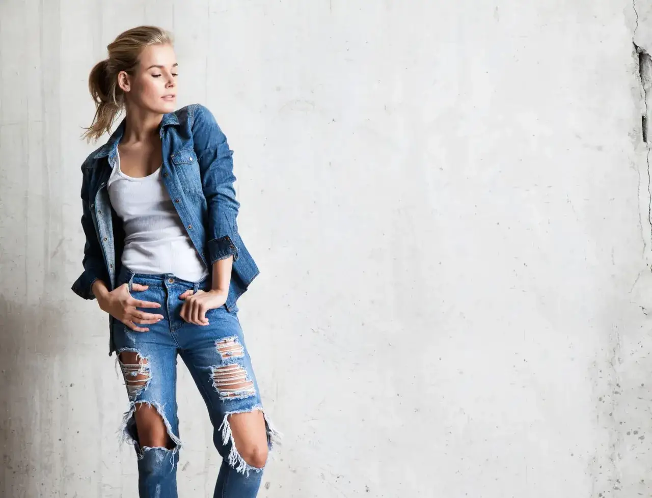Stylowa blondynka w rozdartych jeansach i jeansowej koszuli. Inspiracja, jak nosić koszulę do jeansów.