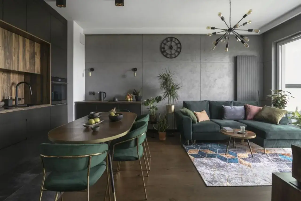 Nowoczesny czarny salon z drewnem, zielona kanapa, owalny stół i designerska lampa.