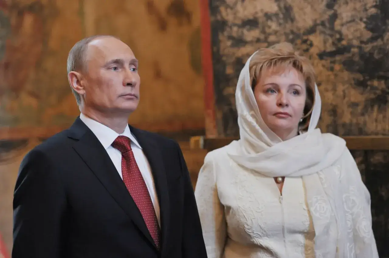 Władimir Putin w garniturze i z żoną w białej chuście i stroju, z naszyjnikiem z pereł.