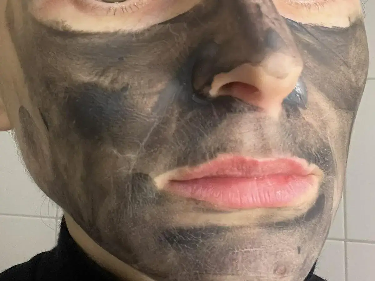 Twarz z nałożoną czarną maseczką rewitalizującą Avon. Skóra wokół ust i nosa jest odsłonięta.