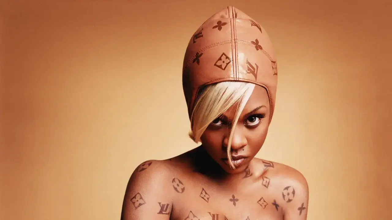 Lil' Kim w skórzanej czapce i z tatuażami Louis Vuitton na ciele.