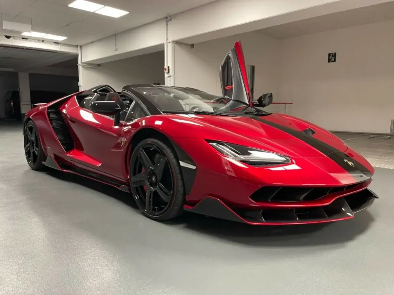 Czerwony kabriolet Lamborghini Centenario z otwartymi drzwiami typu nożycowego.