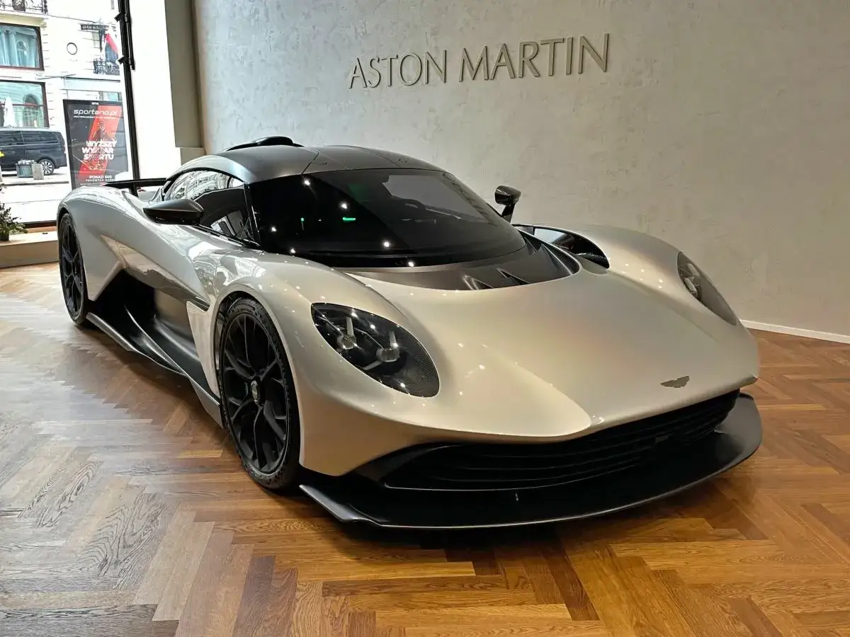 Srebrny Aston Martin na drewnianej podłodze. Zastanawiasz się nad aston martin cena?
