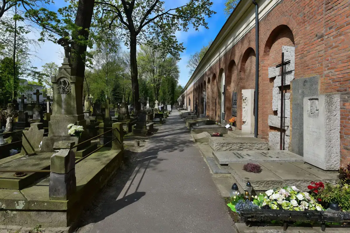 Aleja przez zabytkową nekropolię z nagrobkami i mauzoleami wzdłuż ceglanego muru z arkadami.