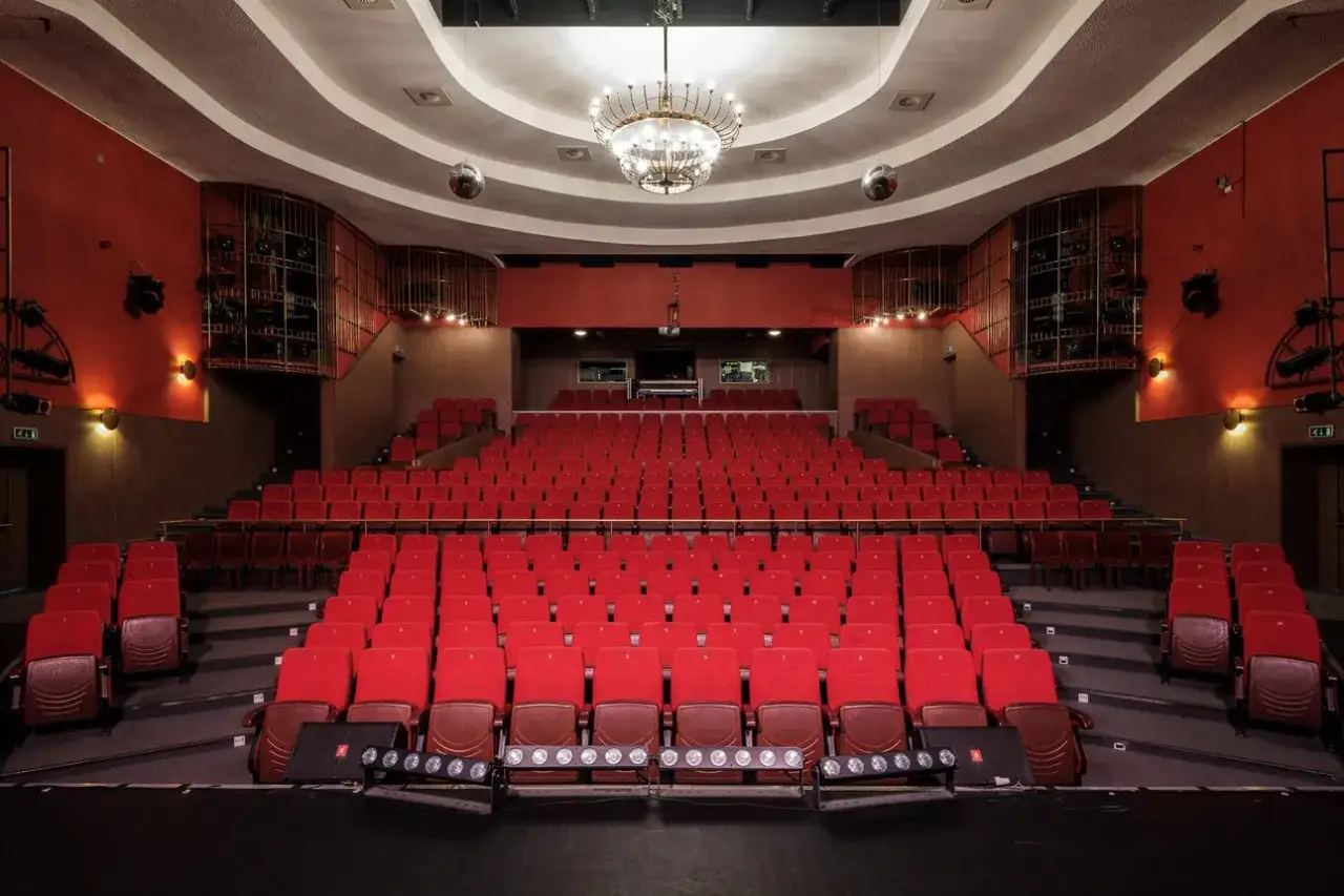 Puste czerwone fotele w teatrze czekają na widzów. Wnętrze z żyrandolem i dyskotekowymi kulami zapowiada bogaty repertuar teatru Rampa.