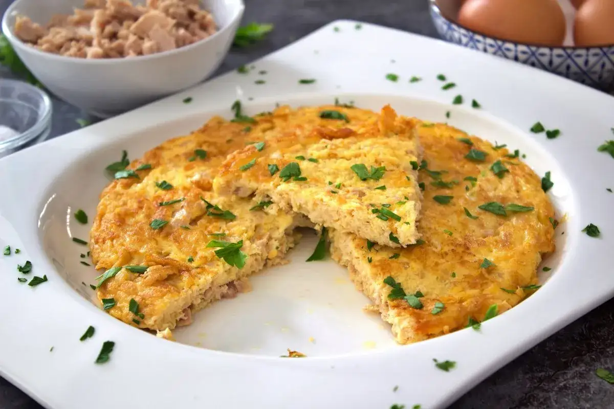Tortilla de atún dorada y esponjosa, espolvoreada con perejil fresco. Un plato sencillo y delicioso.