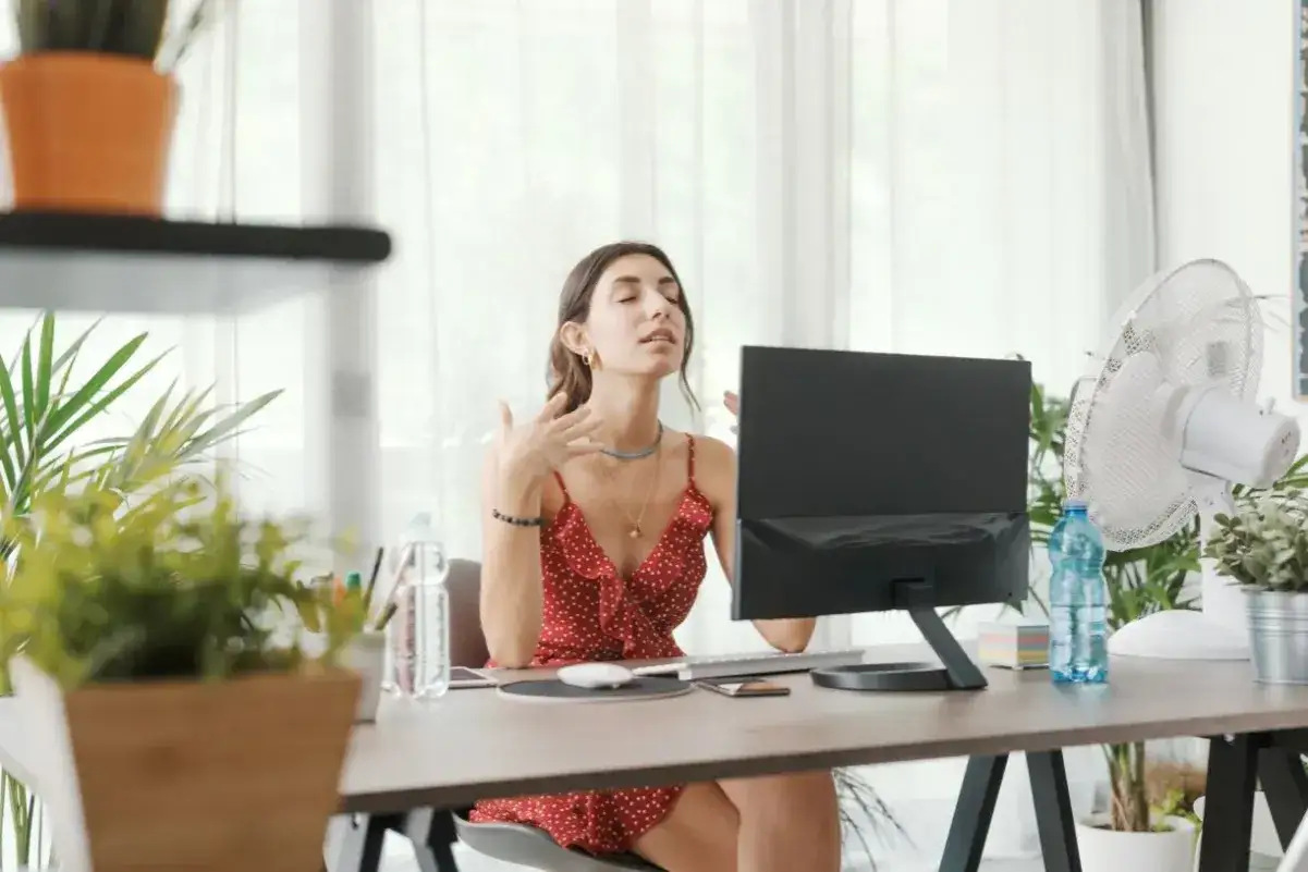 Pracownica zdalna w upalnym biurze, potrzebująca szkoleń BHP dla pracowników zdalnych nowe przepisy prawne, by zapewnić komfort pracy.