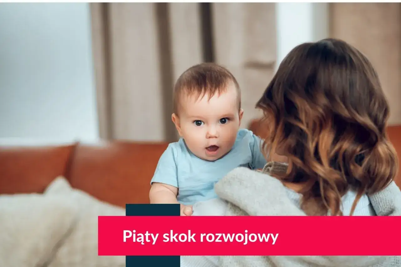 Mama trzyma dziecko na rękach, dziecko patrzy w kamerę z otwartymi ustami.