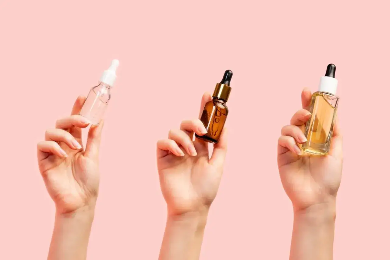 Trzy dłonie trzymają buteleczki z serum. Zastanawiasz się, jakie serum do twarzy po 40. wybrać?
