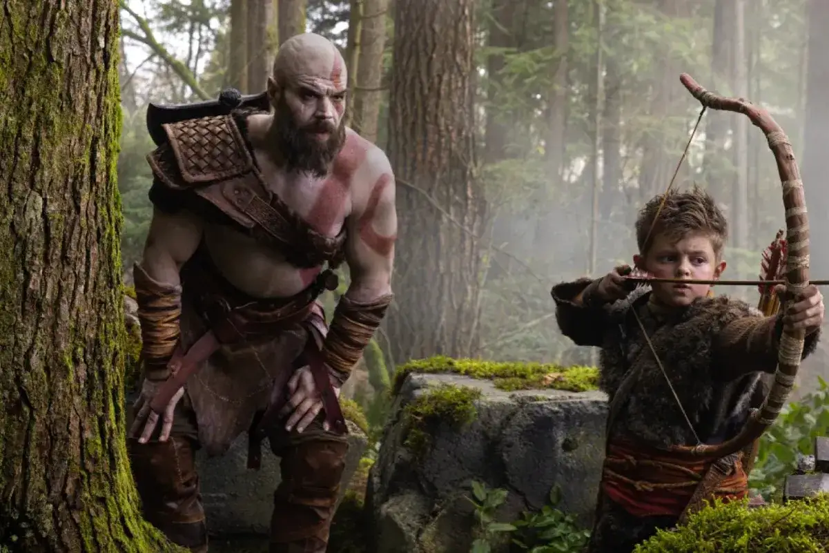 Kratos z synem Atreusem ćwiczą łucznictwo w lesie, przygotowując się do przygód w serialu God of War.
