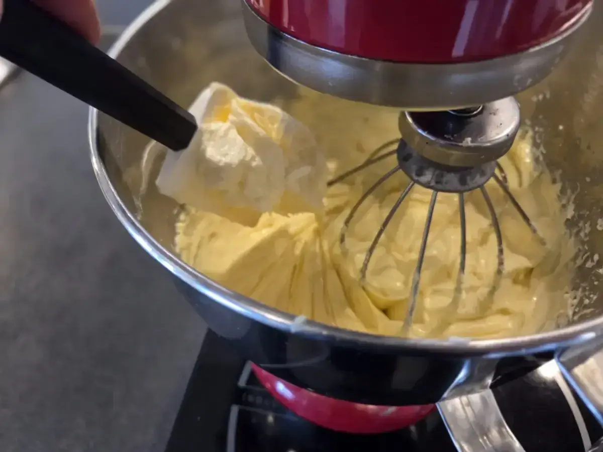 Préparation d'une crème onctueuse pour savoir que faire avec de la crème mousseline. Une spatule ajoute une touche finale à la préparation.