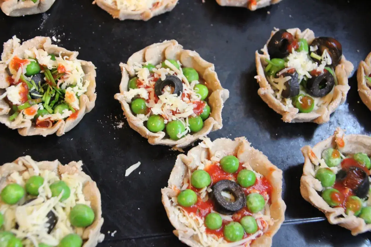 Mini pizze z groszkiem, oliwkami i serem, idealne na podwieczorek.