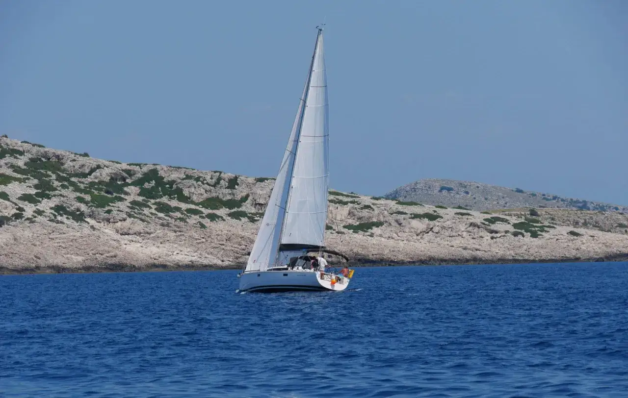 Segelboot gleitet durch das tiefblaue Wasser der kroatischen Kvarner Bucht, vorbei an felsigen, grünen Inseln.