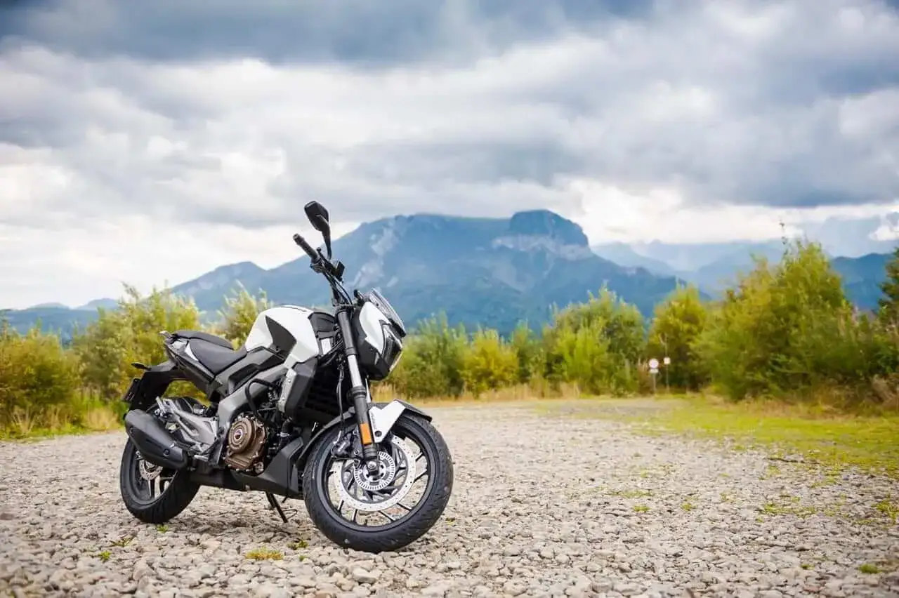 Biało-czarny Bajaj Dominar 400 na tle gór i chmur. Gotowy na przygodę w dziczy.