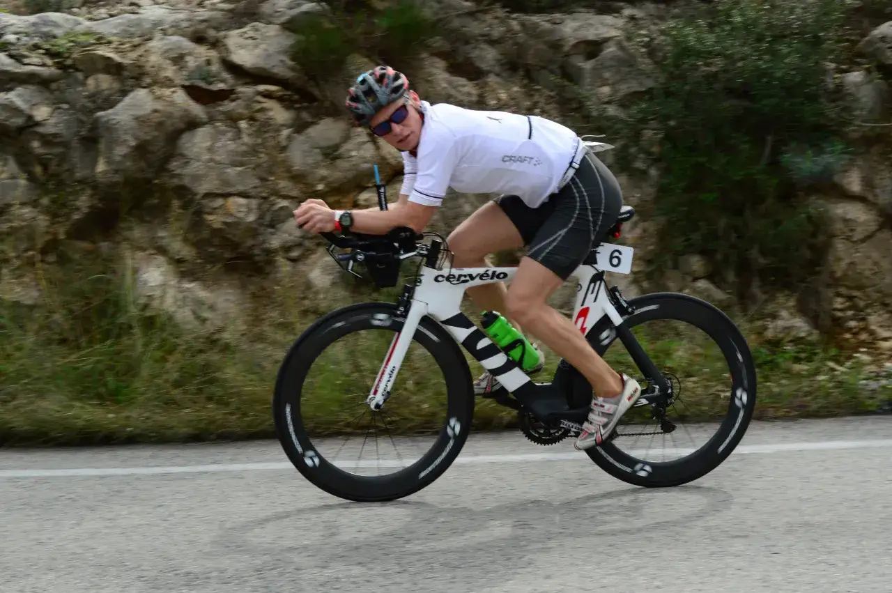 Zawodnik na rowerze triathlonowym pokonuje długi Ironman dystans, pędząc po górskiej trasie.
