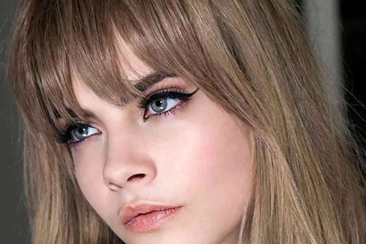 Primer plano de una mujer con flequillo rubio desfilado, delineado de ojos dramático y labios rosados. Muestra varios tipos de flequillo.