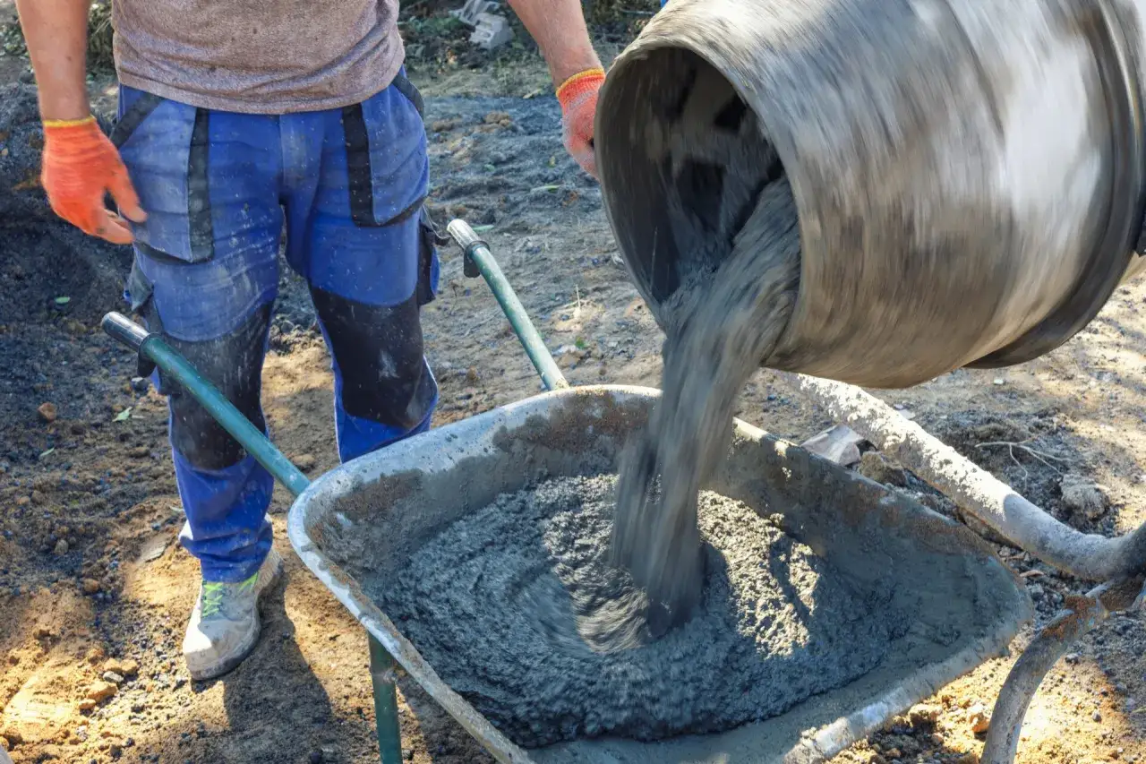Robotnik wylewa beton z betoniarki do taczki. Czy ktory cement lepszy 32 5 czy 42 5?
