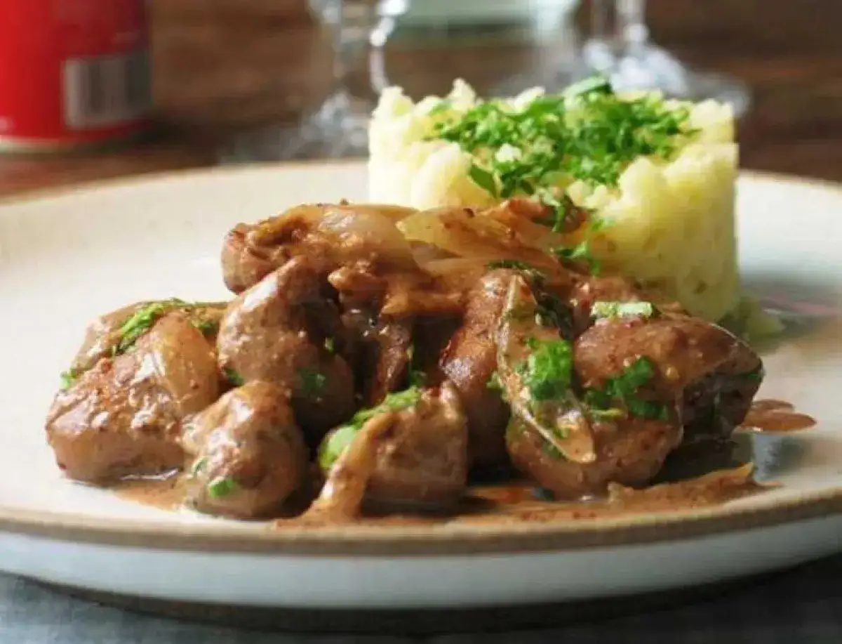 Une assiette de fricassée de rognons de veau, tendres et savoureux, accompagnés d'une purée de pommes de terre onctueuse et garnie de persil frais.