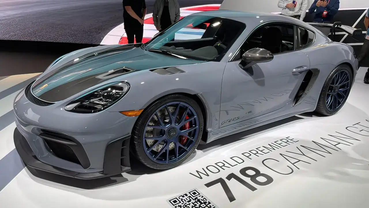 Szary Porsche GT4 RS z niebieskimi felgami i czerwonymi zaciskami hamulcowymi, prezentowany na wystawie.