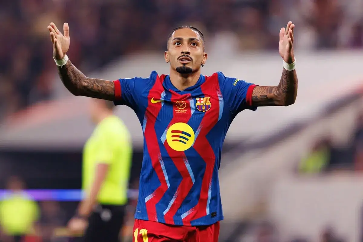 Raphinha, z podniesionymi rękami, świętuje po dołączeniu do FC Barcelony. Jego koszulka zdobi logo Spotify.