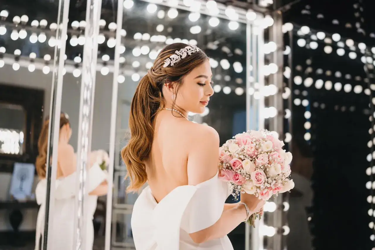 Novia con peinados de novia recogidos elegantes, tiara brillante y ramo de rosas.