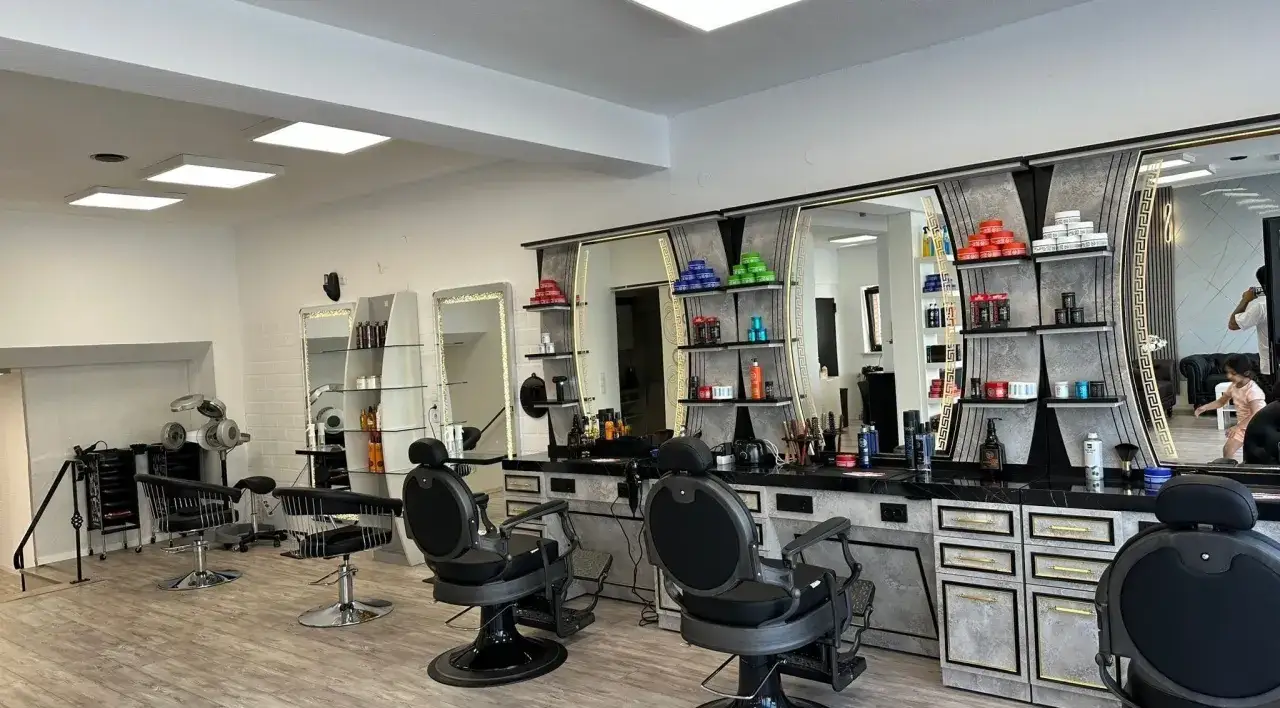 Friseurstuhl und Spiegel in einem modernen Salon mit Regalen voller Kosmetikprodukte.