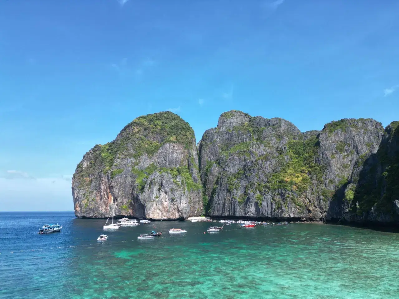 Traumhafte Felsformationen und türkisfarbenes Wasser laden zum Segeln in Thailand ein. Boote ankern in der Bucht.