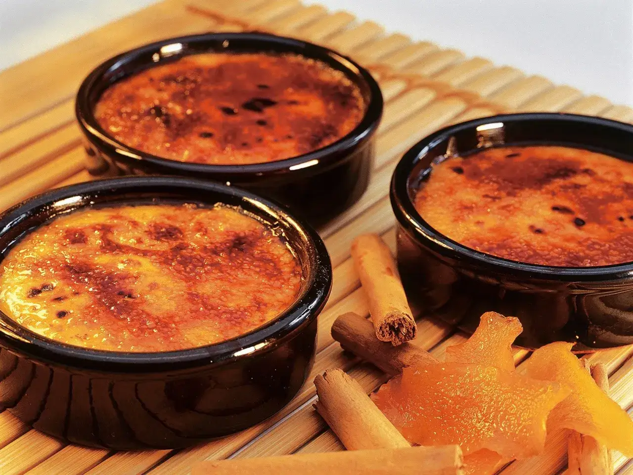 Trois crèmes brûlées aux notes d'agrume et de cannelle, évoquant la crème catalane origine.