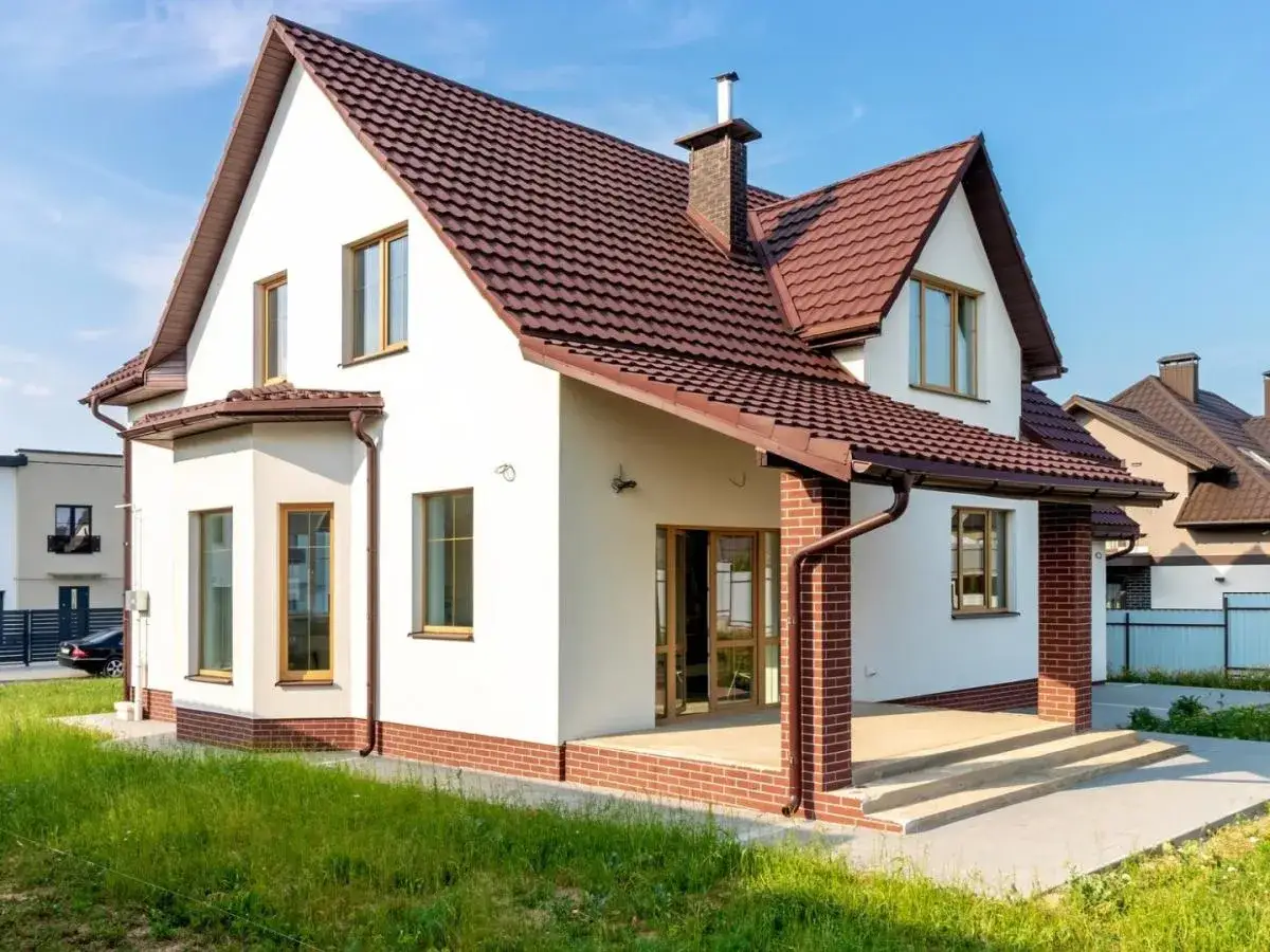 Biała elewacja z ceglanym cokołem i brązowym dachem. Klasyczne, ponadczasowe połączenie, które zawsze wygląda stylowo, pokazując najmodniejsze kolory elewacji.