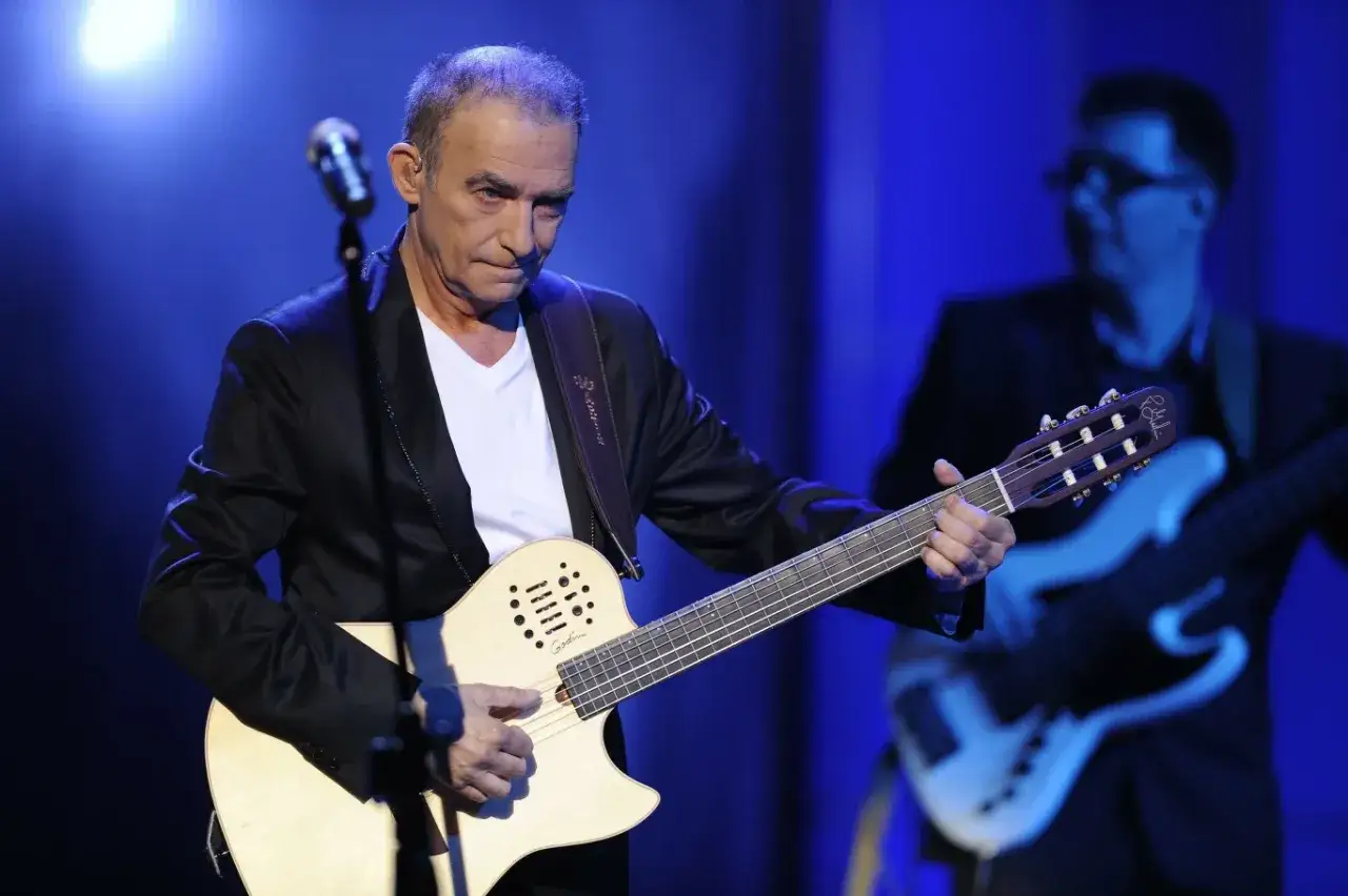 Seweryn Krajewski dzisiaj na scenie, grając na gitarze. W tle basista.