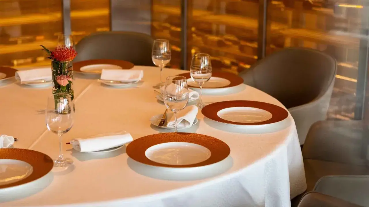 Dressage table gastronomique élégant avec vaisselle raffinée, verres à vin et une petite composition florale.