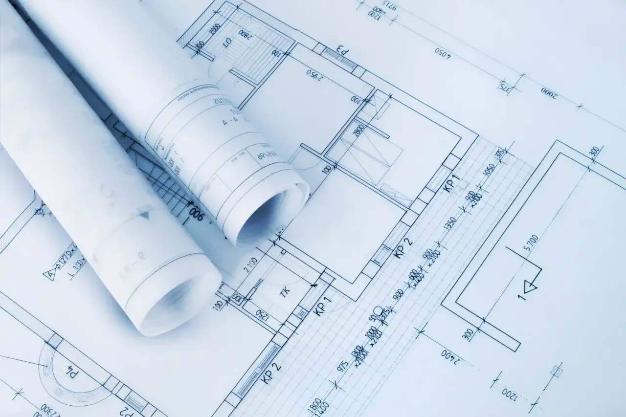 Zrolowane dokumenty z projektem architektoniczno budowlanym, ukazujące plany pomieszczeń i wymiary.
