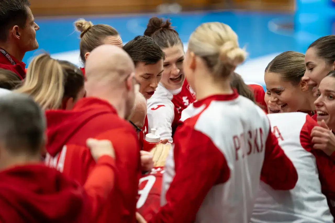 Drużyna piłki ręcznej w czerwonych strojach, zjednoczona przed meczem. Emocje i determinacja na twarzach zawodniczek podczas mistrzostw świata.