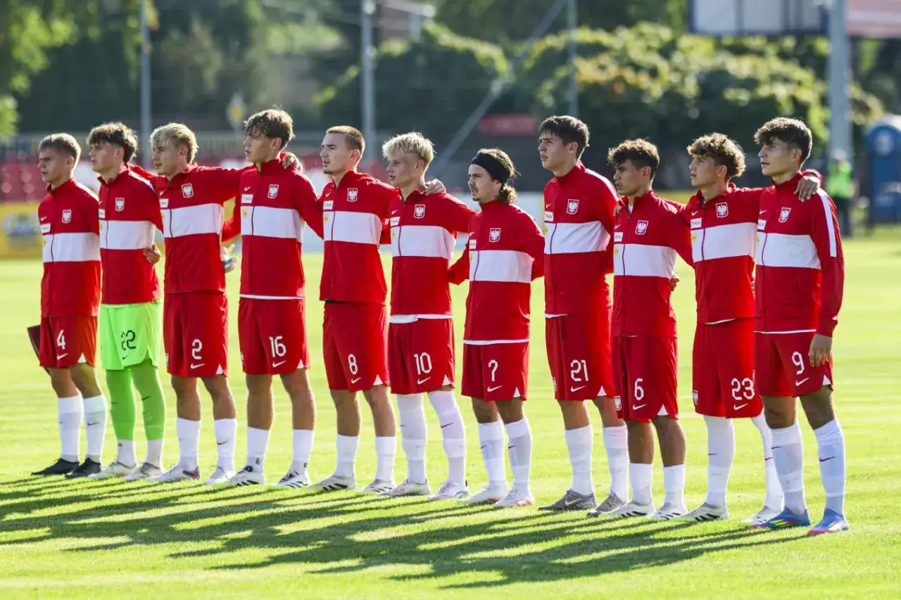 Drużyna Polski na Mistrzostwach Europy do lat 17. Piłkarze w czerwonych strojach z białymi pasami stoją w rzędzie, gotowi do meczu.