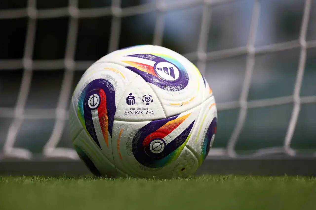 Piłka nożna PKO BP Ekstraklasa na trawie przed bramką.